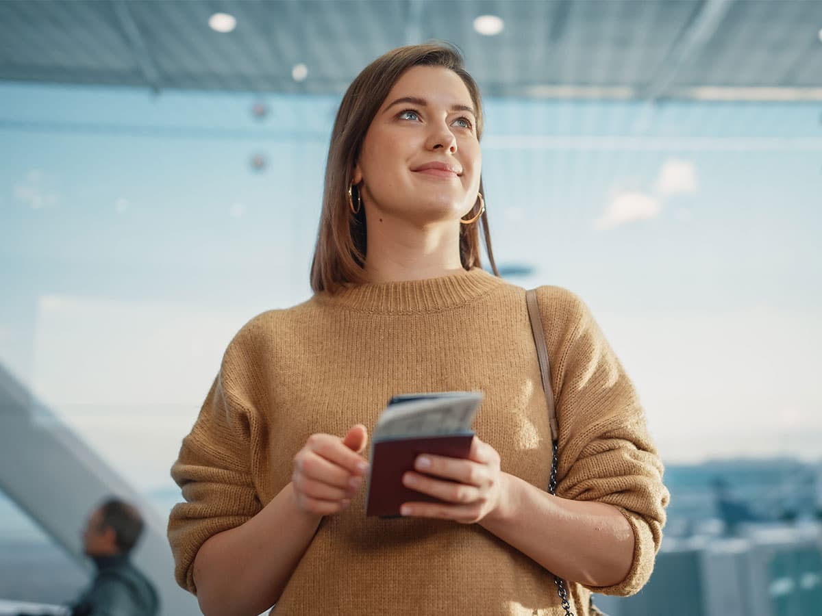A woman holding a cell phone, gazing upwards with a thoughtful expression