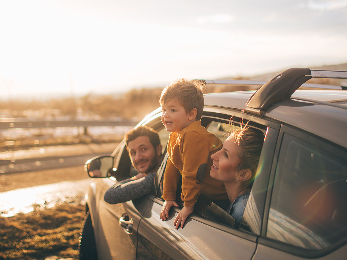A family of four is seated in the back of a car, smiling and enjoying their time together during a road trip